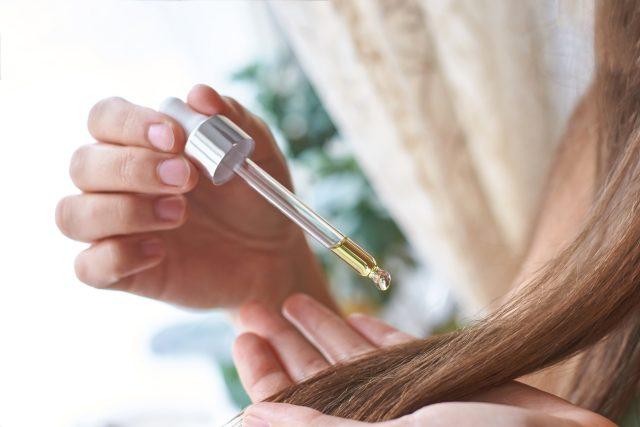Hair care routine. Oil for head. Girl holding dropper