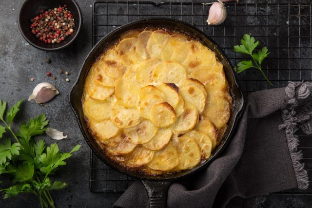 Potato,Gratin,In,Cast,Iron,Pan,,Top,View,,Dark,Background